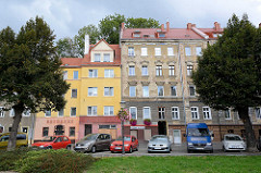 Wohnhäuser und Parkplätze an der Uferpromenade der Lausitzer Neiße in Zgorzelec - eines der Gebäude ist restauriert und mit Fassadenfarbe versehen, das andere Gründerzeitgebäude hat abbröckelnden Putz und ist renovierungsbedürftig.