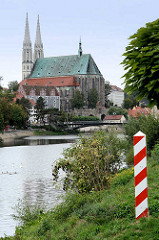 Blick vom Ufer der Neisse in Zgorzelec zur evangelischen Pfarrkirche St. Peter und Paul und das Waidhaus - im Vordergrund der Grenzpfahl in den polnischen Farben rot / weiss.