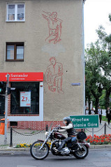 Schlichtes Wohnhaus mit Rauhputzfassade und Fresko / Fassadendekor, arbeitende Männer  - Arbeiter Zimmermann und Maurer.