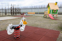 Kinderspielplatz mit Schaukeltier, Holzhaus mit Rutsche / Frauengefängnis Hamburg Billwerder.