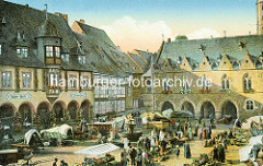 Historisches Bild vom Goslarer Marktplatz - lks. das Kaiser Worth, re. das Rathaus mit Blumen vor den Fenstern - Markttreiben auf dem Platz, Fuhrwerke mit Planen abgedeckt; Verkaufsstände mit Gemüse - Passanten.