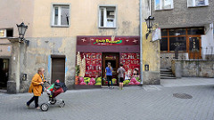 Eisdiele / Eisverkauf mit bunter Fassade, Eissorten - Kinder vor dem Geschäft, graue Hausfassaden in Kłodzko / Glatz.