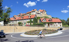 Fahrradfahrer im Kreisverkehr - mit Blumen bepflanztes Rondell; im Hintergrund Gebäude auf dem Münzenberg in Quedlinburg.
