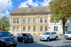 Straßenkreuzung, Autoverkehr in Aschersleben - Gründerzeitgebäude, kannelierte Säulen und Stuckdekor an der Hausfassade.