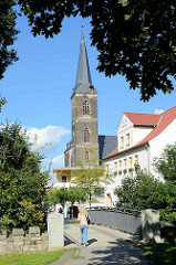 St. Stephani Kirche in Aschersleben; gotische Hallenkirche, erbaut von 1406 - 1507. Im Vordergrund eine Fussgängerbrücke über die Eine.