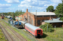 Blick auf das Bahngelände vom ehem. Bahnbetriebswerk BW Aschersleben; Bahnwaggons stehen auf den Gleisen - Lokschuppen, historische Backsteinarchitektur.