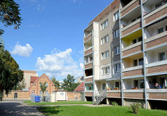 Alt + neu /  Architektur in Aschersleben; mehrstöckiger Wohnblock, Plattenbau mit Balkons - im Hintergrund historisches Doppelhaus, Ziegelgebäude mit Backsteinmauer.
