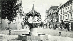 Altes Bild vom Hennebrunnen in Aschersleben; die Brunnenanlage zeigt eine durch einen Baldachin überdachte gegliederte Säule, auf der acht eigenartige Bronzeputten sitzen. Der Brunnen wurde von Georg Wrba entworfen und 1906 eingeweiht.