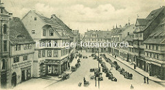 Altes Bild vom Quedlinburger Marktplatz - Marktstände in einer Reihe; Geschäfte - im Vordergrund Fassadenaufschrift Drogen, Colonialwaaren, Cigarren, Farben, Tapeten, Wachstuch; Pferdefuhrwerke stehen am Strassenrand.