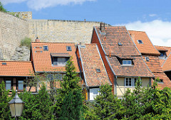 Historische Häuserreihe, Wohnhäuser mit unterschiedlichen Breiten - Architektur in Quedlinburg; dahinter die Schlossmauer vom Schloßberg.