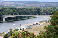 Lauf der Elbe bei Mělník in Tschechien - Lagergebäude am Flußufer, ein Sportboot fährt flussabwärts.