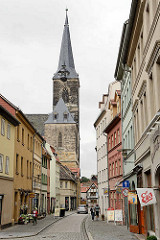 Strasse mit Geschäften - Eisladen mit Werbefahnen an der Hauswand - Kirchturm der St. Stephani Kirche in Aschersleben; gotische Hallenkirche, erbaut von 1406 - 1507.