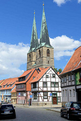 Fachwerkhäuser und Kirchtürme der St. Nikolai Kirche in Quedlinburg; blauer Himmel, weiße Wolken.