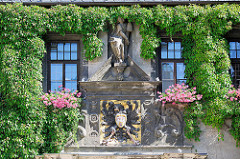 Eingang vom Quedlinburger Rathaus, die Fassade ist mit Kletterpflanzen bewachsen - das zweigeschossige gotische Gebäude ist eines der ältesten Rathäuser Mitteldeutschlands. Über dem Eingangsportal befindet sich als Brustschild eines schwarzen Rei