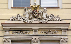 Architektur der Stadt Hradec Králové / Königgrätz - Arkanthusdekor im Fenstersturz, Putten halten das Wappen der Stadt - stehender Löwe mit G.