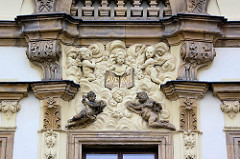 Dekorelemente am Eingang des Bischofspalasts in Hradec Králové / Königgrätz; Putten und Engelsfiguren, Engel mit Flügel - eine Figur hält ein Tableau mit der lateinischen Gruß- und Segensformel AVE.
