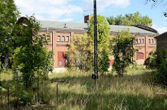 Alte Industriearchitektur - Ziegelgebäude, Güterbahnhof Aschersleben - Bahngleise mit Gras überwuchert.