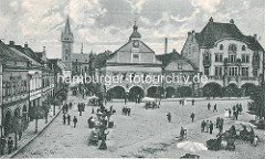 Historische Aufnahme vom Marktplatz in Dvůr Králové nad Labem / Königinhof an der Elbe; Blick auf das Rathaus - auf dem Platz sind Marktstände aufgebaut, Passanten schlendern auf der Strasse. Im Hintergrund die ehem. romanische Dekanatskirche Joh