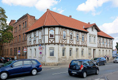 Verkehrsstraße in Aschersleben - Geschwister Scholl Strasse; Gebäude mit Fachwerk-Stockwerk; daneben Industriearchitektur, Backsteinfassade.