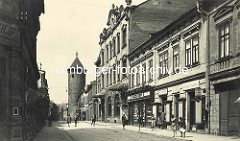 Historische Straßenansicht der Straße Havlíčkova in Dvůr Králové nad Labem / Königinhof an der Elbe - Kinder spielen auf der Strasse, Geschäftsinhaber stehen in der Ladentür; im Hintergrund ein alter Wehrturm der ehem. Stadtbefestigung.