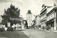 Historische Aufnahme vom Prager Tor in Mělník  - Passanten auf dem Bürgersteig, parkendes Auto.