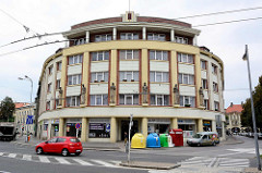 Rundes Eckhaus - Art Deko Fassade mit Figurenschmuck, Geschäfte im Erdgeschoss; Wohnblock in Hradec Králové / Königgrätz.