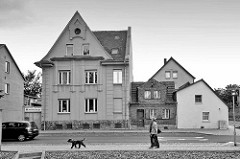 Wohnhäuser in Aschersleben - unterschiedliche Baustile und Hausgrößen; Spaziergänger mit Hund - Schwarz Weiß Bild.