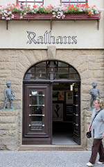 Marktseite vom Rathaus in Aschersleben - Eingang mit Schriftzug und Bronzeskulpturen.