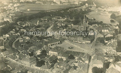 Historische Luftaufnahme von Nymburk / Neuenburg an der Elbe in Tschechien; in der Bildmitte der Marktplatz der Stadt, dahinter die Kirche und das Wasserwerk.