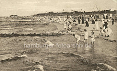 Historisches Foto vom  Ostseebad Zingst - Badegäste am Wasser; Kinder / Mädchen in Kleidern mit den Füssen im Wasser - Frauen in langen Kleidern mit Hüten am Strand.