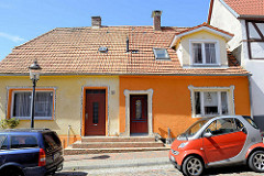Doppelhaus / Wohnhaus in der Mühlenstraße von Ribnitz-Damgarten; farblich mittig geteilt, gelb + orange - Mosaik Verzierung um Türen und Fenster