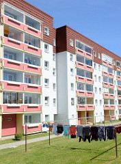 Wohnblock mit farblich abgesetzten Balkons, Wäsche hängt zum Trocken auf der Wiese; Jiciner Straße in Ribnitz Damgarten.