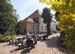 Das Museum Elbinsel Hamburg-Wilhelmsburg hat seinen Sitz im alten Hannoversche Amtshaus. In seinen Räumen zeigt das Regional-Museum die Geschichte und bäuerliche Kultur Wilhelmsburgs. In dem Museumscafè sitzen Gäste auf dem Kopfsteinpflaster.
