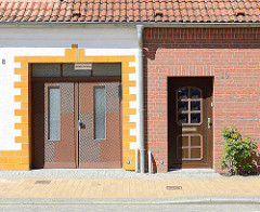 Hauseingänge unterschiedlich gestaltete Fassaden, Nördlicher Rosengarte / Ribnitz-Damgarten; weisse Hausfassade mit gelb abgesetztem Eingang / Ausfahrt - Ziegelfassade.
