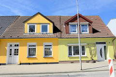 Restaurierte Wohnhäuser mit ausgebautem Dach - Doppeldachfenster und unterschiedlich gelb gestrichene Hausfassade; Bahnhofstraße in Ribnitz Damgarten.