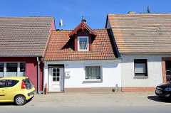 Schmales Haus, eingezwängt in andere Reihenhäuser - Mansardenfenster mit geschnitztem Holzgiebel - Barther Straße im Ortsteil Damgarten; Ribnitz-Damgarten.