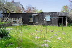 Altes Holzgebäude mit Wellblech als Dach - Terrasse mit Betonwand und diagonalen / dreieckigen farbigen Glassteinen - ehem. Ferienhaus im Ostseebad Ahrenshoop.