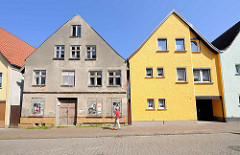 Restauriertes Wohnhaus mit gelb gestrichener Fassade, verfallenes Gebäude mit abbröckelndem Putz und Luken verschlossene Fenster; Architekturbilder aus Barth / Alt + Neu.