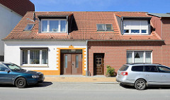 Doppelhaus mit unterschiedlich gestalteter Fassade, Nördlicher Rosengarten / Ribnitz-Damgarten; weisse Hausfassade mit gelb abgesetztem Eingang / Ausfahrt - Ziegelfassade.