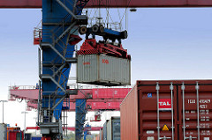 Die Ladung eines Containerzugs wird im Containerbahnhof Hamburg Altenwerder gelöscht - einer der Container wird mit einem Portalkran vom Güterwaggon zum Sattelauflieger transportiert.