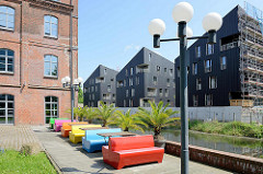 Altbauten / Neubauten, moderne und historische Architektur am Kaufhauskanal in Hamburg Harburg -  Wohnquartier Maritimes Wohnen; bunte Plastikbänke an der Kanal Promenade.