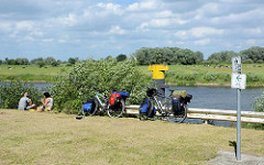 Fahrradtour - Rast an der Elbe bei Bleckede; hoch bepackte Fahrräder / Fahrradtaschen - Picknick am Wasser.