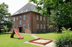 Kasernengebäude der 1936/37 errichteten Bismarck Kaserne in Wentorf bei Hamburg; jetzt Wohnnutzung - Kinderspielplatz mit Rutsche und Sandkasten / Rasen.
