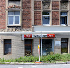 Jugendstilwohnblock / Eckgebäude in Hamburg Wilhelmsburg; Restbestand von im Krieg zerbombten Wohnbebauung. Erdgeschoss Fassade mit gelben Kacheln versehen - Ladenlokal, Frühstück.
