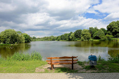 Blick auf den Mühlenteich / Glinder Au - Bäume am Wasser, blauer Himmel - weisse Wolken / Holzbank, Ruhebank am Ufer des Sees.