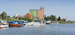 Hafen von Bleckede an der Elbe; Sportboote in der Marina, ein Binnenschiff liegt am Hafenkai. Speichergebäude / Silo und Wohnhäuser am Hafenrand.