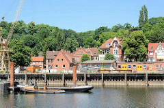 Werftkai an der Elbe / Mündung vom Elbe-Lübeck-Kanal in Lauenburg, Arbeitsschiffe und Werftkran; am Ufer Wohnhäuser.