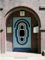 Mit farblich abgesetztem Leistendekor - Eingangstür, Backsteinarchitektur der 1930 / 40er Jahre - Werkswohnungen in Hamburg Heimfeld.