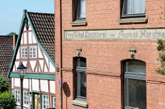 Werkstattgebäude - Backsteinarchitektur, Bau & Möbeltischlerei, daneben ein Fachwerkhaus mit grün gestrichenen Balken - Architekturbilder aus Lauenburg / Elbe.