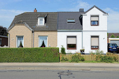 Doppelhaus mit unterschiedlicher Fassadengestaltung - Klinker und weisse Putzfassade, Hecke oder Zaun; Architektur in Brunsbüttel, Kreis Dithmarschen.